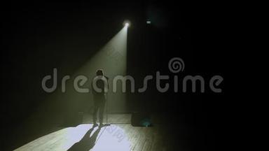 一个男人在黑暗中拿着麦克风上台的剪影。 发言人。